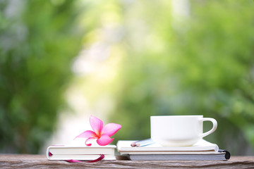 White cup with plumaria flower and notebooks