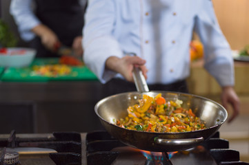 Obraz na płótnie Canvas chef flipping vegetables in wok
