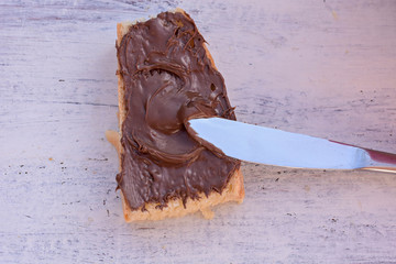 Bread whit chocolate nougat cream at light wooden table/ sweet breakfast/ good morning/ starting a day