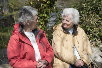 Two senior woman chatting outdoors on a sunny day