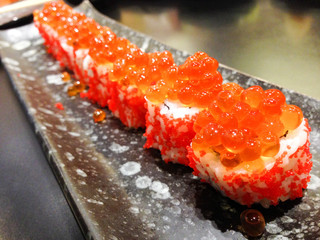 Japanese rice roll with Salmon roe on top and seaweed inside, lay on Japan disk style. Shooting in an International buffet restaurant.