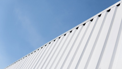 Metal white sheet for industrial building and construction on blue sky background. Roof sheet metal or corrugated roofs of factory building or warehouse.