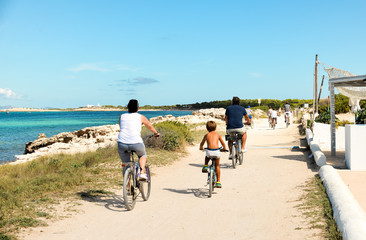 Ibiza, Spain - October 5, 2017 : View of road with car and bicyclist riding on pear. Big green palm tree on Ibiza and Formentera island beach. Summer holidays and free time at sunny weather near sea.