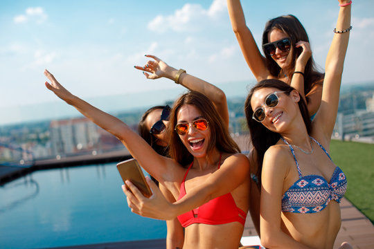 Four young women in a penthouse near the pool doing selfie in a bikini