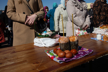 wicker basket stands with an easter cake and a burning candle on the street in the morning near the...