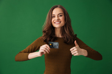 Young cheerful woman holding credit card make thumbs up gesture.