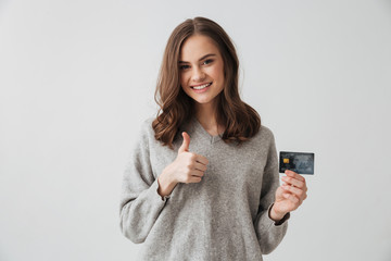 Smiling brunette woman in sweater holding credit card