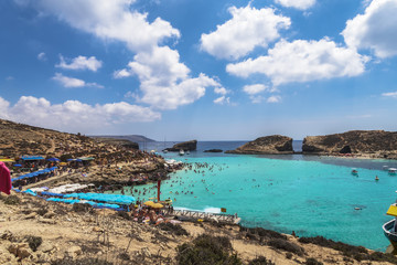 Comino Island, Malta Blue Lagoon panoramic landscape with bathers. The most famous and crowded beach in Malta with crystal clear waters.