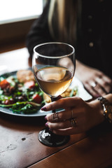 Female hand with glass of wine and food in the background