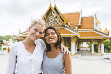 Thailand, Bangkok, portrait of two smiling friends in front of temple