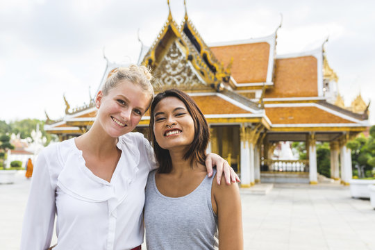 Thailand, Bangkok, portrait of two smiling friends in front of temple
