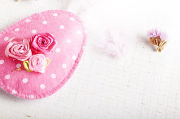 Handmade patchwork pink and lilac felt easter eggs on white wooden table