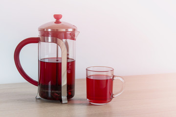 Hibiscus tea in a tea pot. Karkade tea or red sorrel tea in glass pot and cup on white background with copy space.