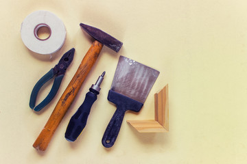 Old used household instruments, tools for home reparation on yellow background with copy space. Hammer, pliers, screwdriver, spatula. Top view, Flat lay.