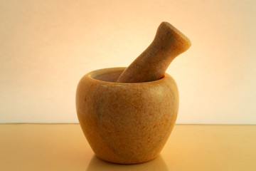 Mortar and pestle for grinding and mixing ingredients on a colored background in backlight with a...