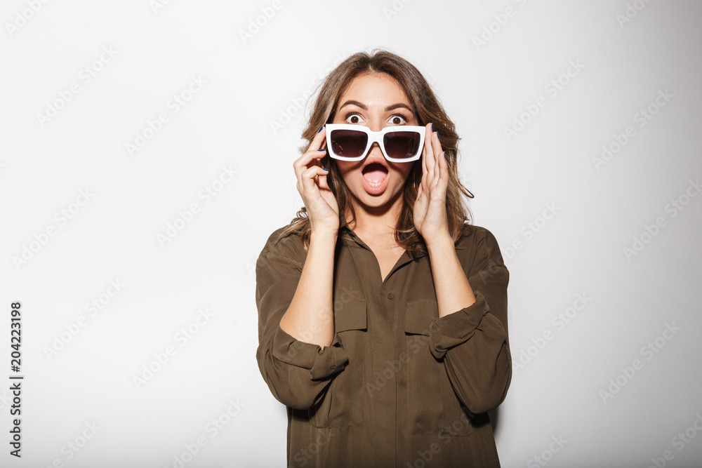 Poster Portrait of a shocked young woman looking over sunglasses