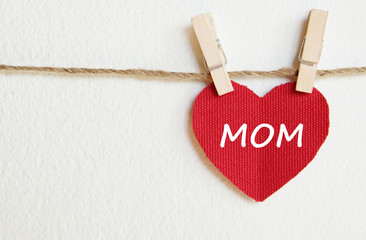 Happy mother's day greeting card, Love mom word on red fabric heart shape hanging over white...