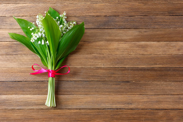 Lily flower bouquet tied with red ribbon on wooden retro background with copy space