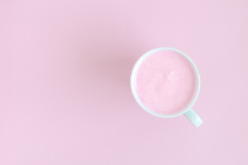 High angle view of cup of fruit smoothie on rose background.
