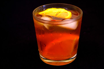 Iced tea with lemon and orange on the black background. Refreshment