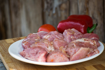 Raw kebab from meat on a wooden board with vegetables