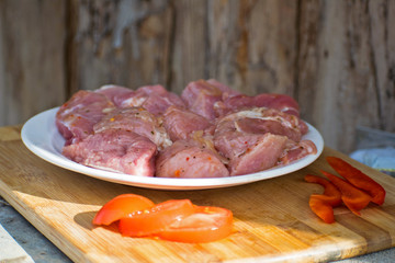 Raw kebab from meat on a wooden board with vegetables