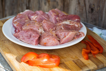 Raw kebab from meat on a wooden board with vegetables