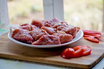 Raw kebab from meat on a wooden board with vegetables