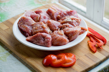 Raw kebab from meat on a wooden board with vegetables