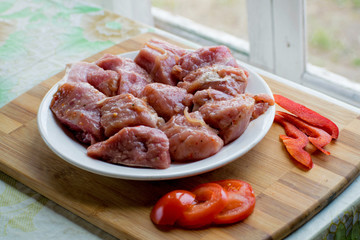 Raw kebab from meat on a wooden board with vegetables