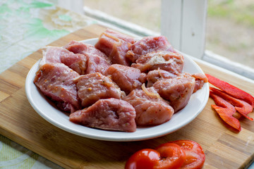 Raw kebab from meat on a wooden board with vegetables