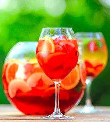 Summer cocktail. Fruit cocktail on green background. Citrus fruits, berries, strawberries, blueberries, mint, ice.