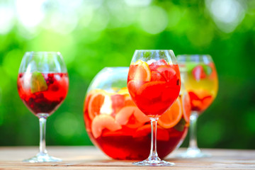 Summer cocktail. Fruit cocktail on green background. Citrus fruits, berries, strawberries, blueberries, mint, ice.