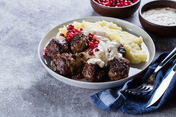 Homemade beef and pork meatballs with mashed potatoes and lingonberry sauce on a gray stone concrete background table. Lunch Dinner Food Concept