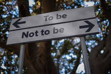 To be or not to be: road sign with opposite direction arrows. Problem or doubt thinking concept.