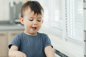 The little boy in the kitchen eagerly eating rice with a spoon independently