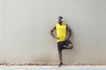 Sporty afro man standing near old wall, doing morning gymnastics