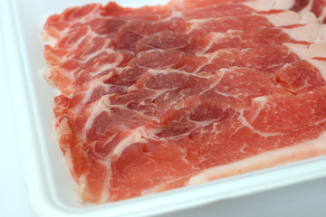 食品トレーに入った豚肉　ロース肉　白背景　コピースペースあり	