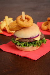 hamburger with lettuce cheese and onion rings on top