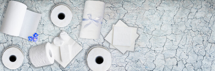 Paper tissue, white toilet  paper rolls, towels, napkins, cotton pads stacked on old gray marble...