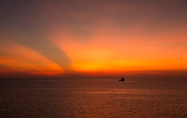 supply boat in the sea in the evening sunlight reflect with orange sunset for abstract transportation logistic concept