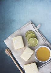Vertical image of three lemon cake slices with limes and honey on a blue background 