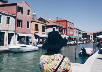 Back view of a Girl with hat over the canal at Murano in Venice