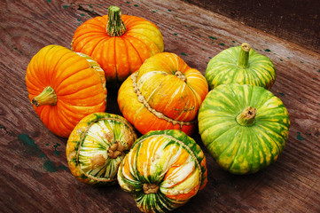 Orange and green pumpkins on brown table.