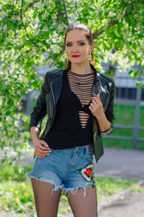 Fototapeta premium Charming woman dressed in a leather jacket near bird-cherry tree