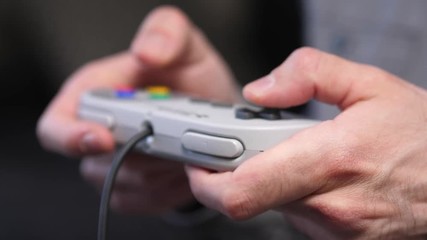 Closeup of hands playing on a retro gaming console controller, pressing the buttons. - Powered by Adobe