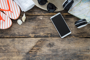 Naklejka premium Koncepcja wakacje, przygotowanie do podróży, smartfon i paszport w okularach i klapki na starym drewnianym stole