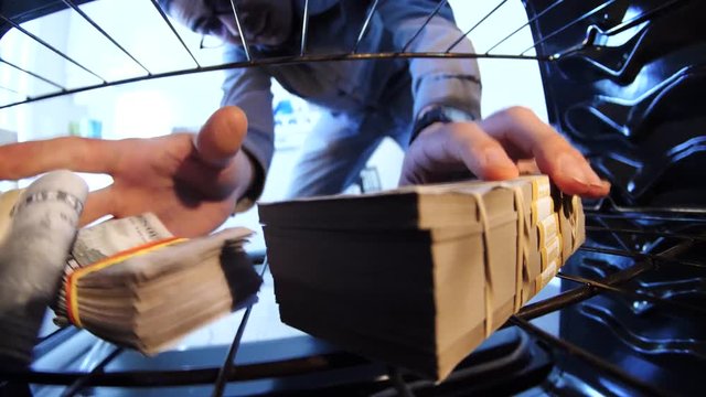 Funny absurd video concept of a man hiding his money inside a kitchen oven.