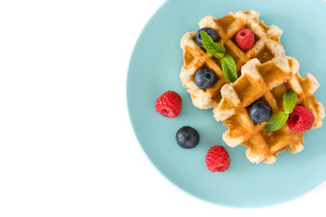 Traditional belgian waffles with blueberries and raspberries, isolated on white background. Top view. Copyspace
