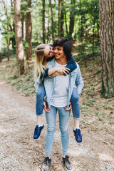 Young romantic couple hugging, kissing and having fun while they have vacation in forest